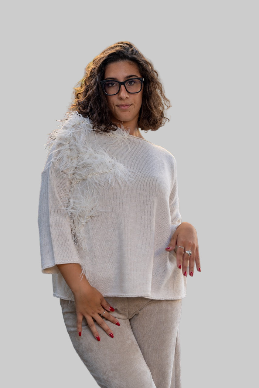Woman wearing a white sweater with lace details and beige pants on a sidewalk.