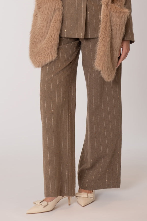 Woman wearing a brown suit with a fur vest against a white background