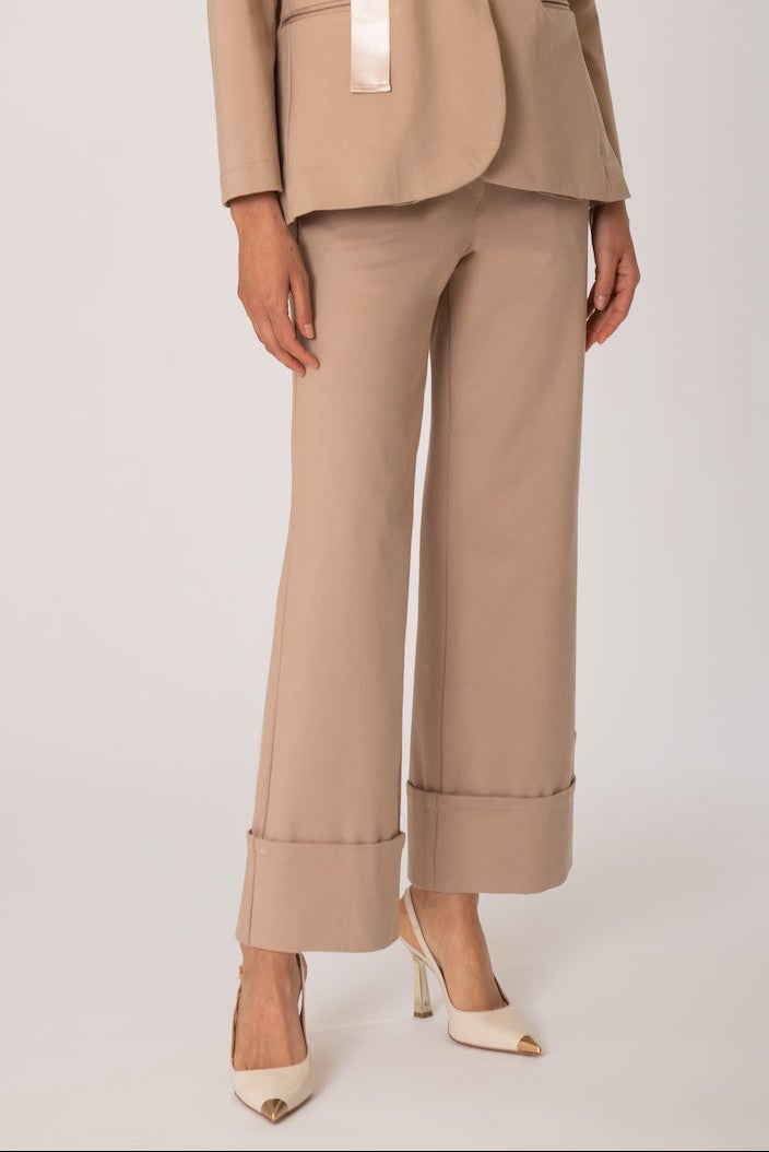 Woman wearing a beige suit with fur collar against a white background