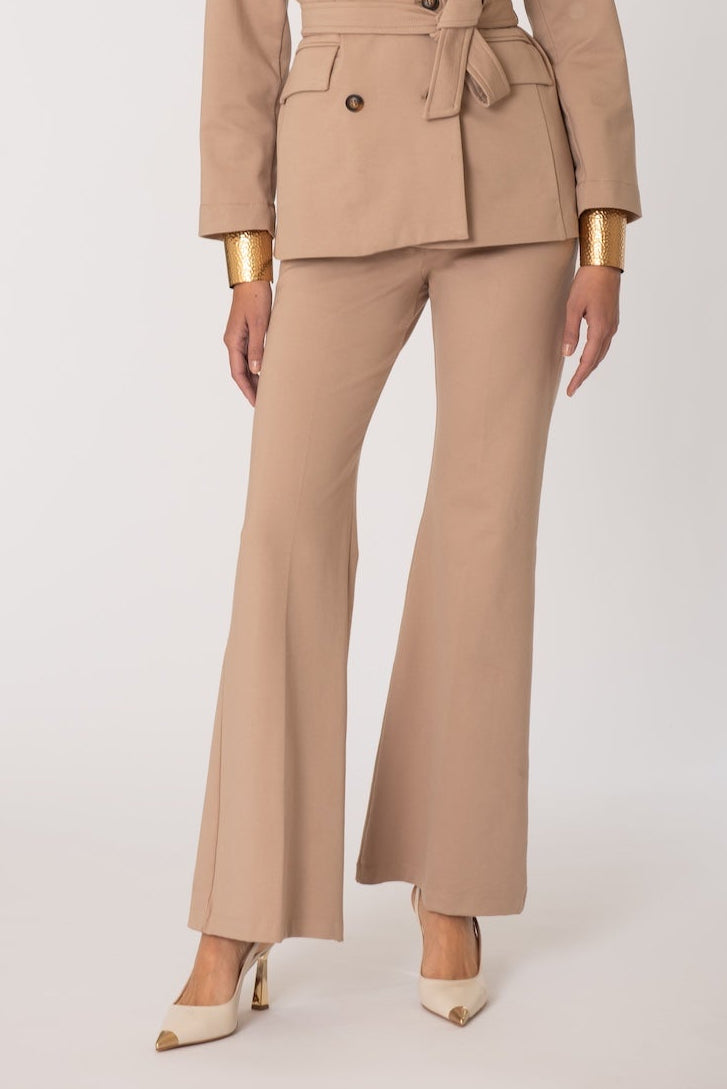 Woman wearing a beige suit with gold accents on a white background